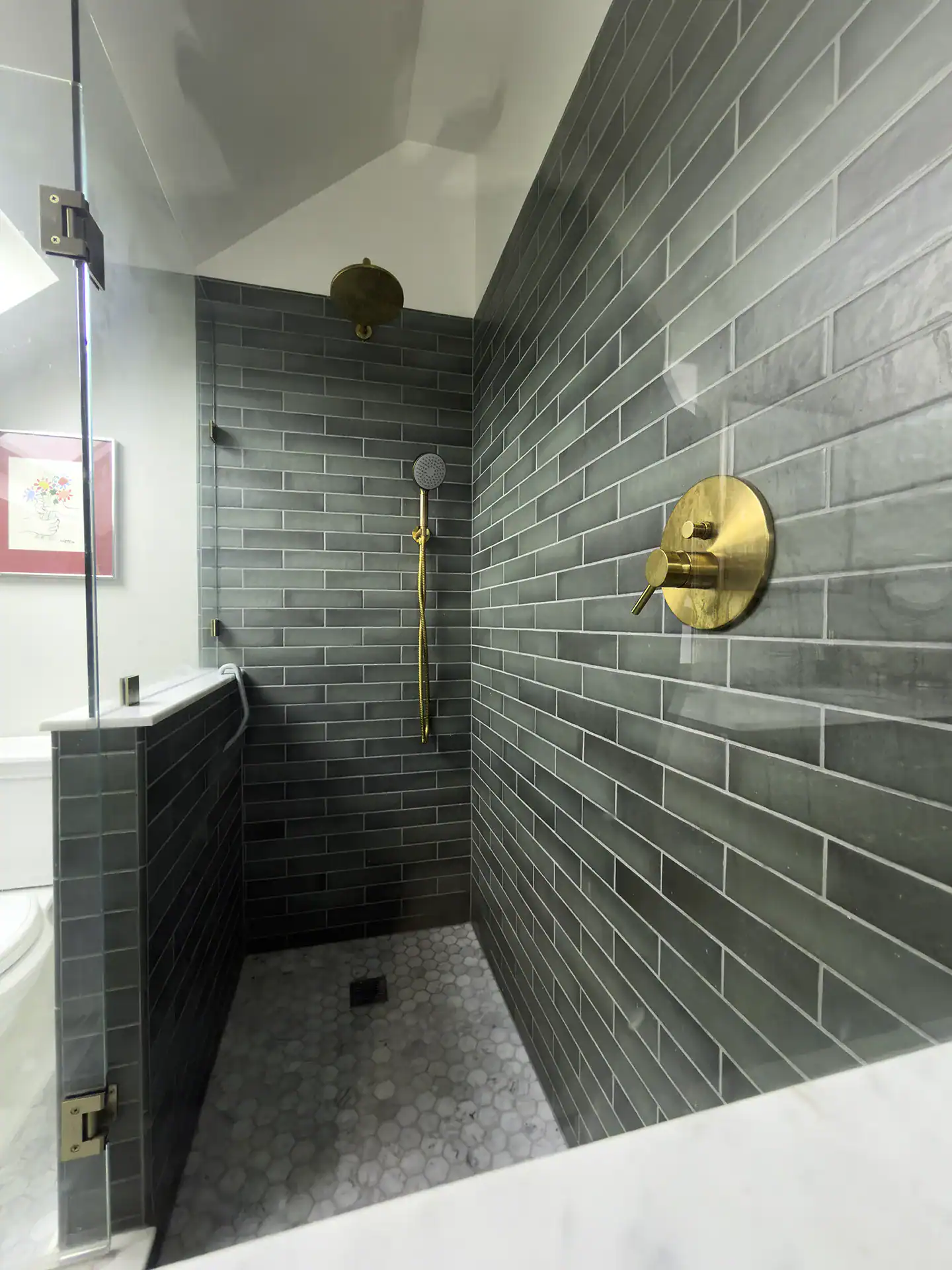 Walk-in shower with green tile walls and marble mosaic floor