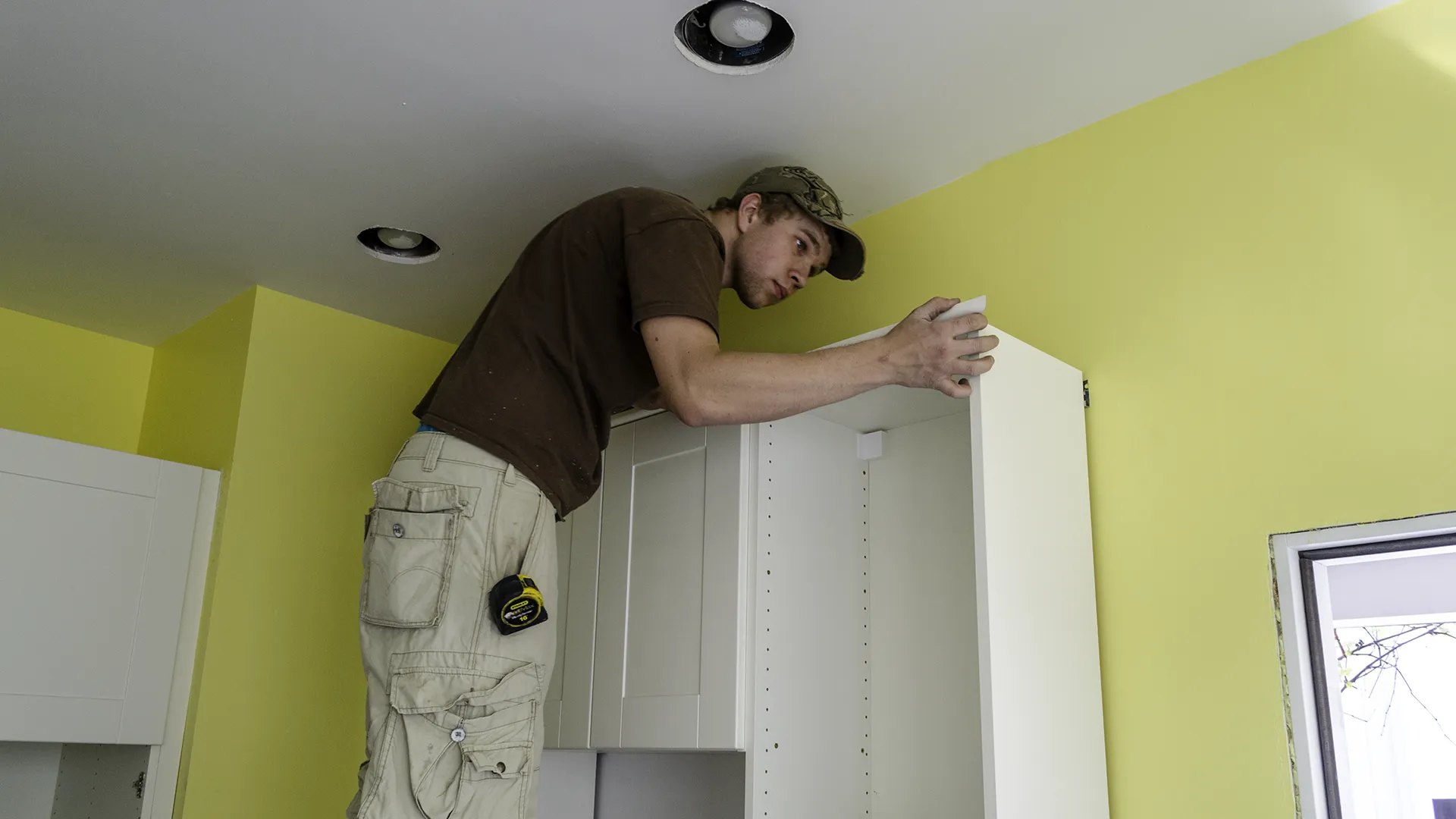 Installer aligning and leveling IKEA wall cabinets during a kitchen remodel